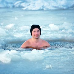 Badefreuden in arktischer Umgebung: Ein Mann mit Mütze freien Oberkörper in einem Eisloch