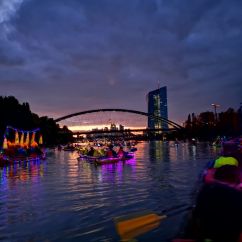 Schön iluminierte und geschmückte Boote in der Abenddämmerung vor der eindrucksvollen Skyline von Frankfurt