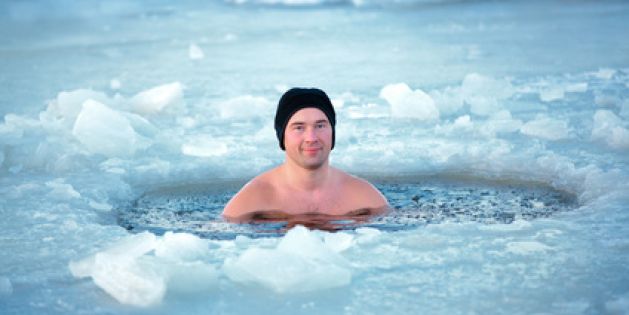 Badefreuden in arktischer Umgebung: Ein Mann mit Mütze freien Oberkörper in einem Eisloch